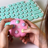 Pink hamster game fidget toy in hands with keyboard in background